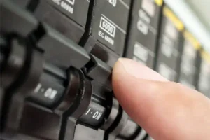 Close-up of a person's finger switching on a circuit breaker in an electrical panel during a circuit breaker installation in Brea, California.