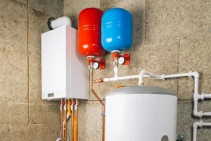 Wall-mounted boiler system with red and blue expansion tanks and a white water heater, professionally installed in Brea, California, connected by copper and PVC pipes in a utility room.