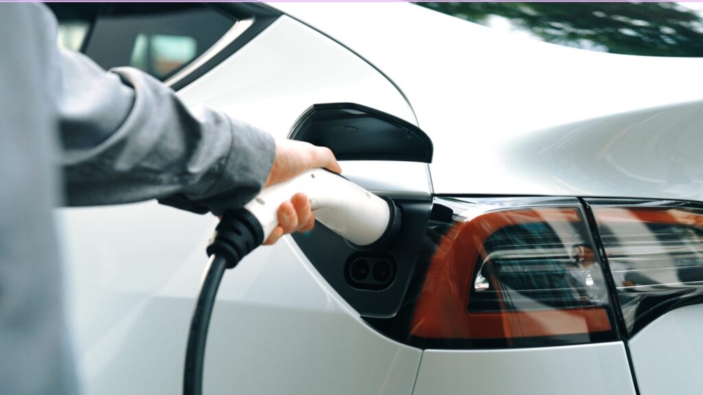 A person plugs a charging cable into an electric car’s charging port, showcasing how EV charger installations in Brea are making it easier for homeowners to power up at home.