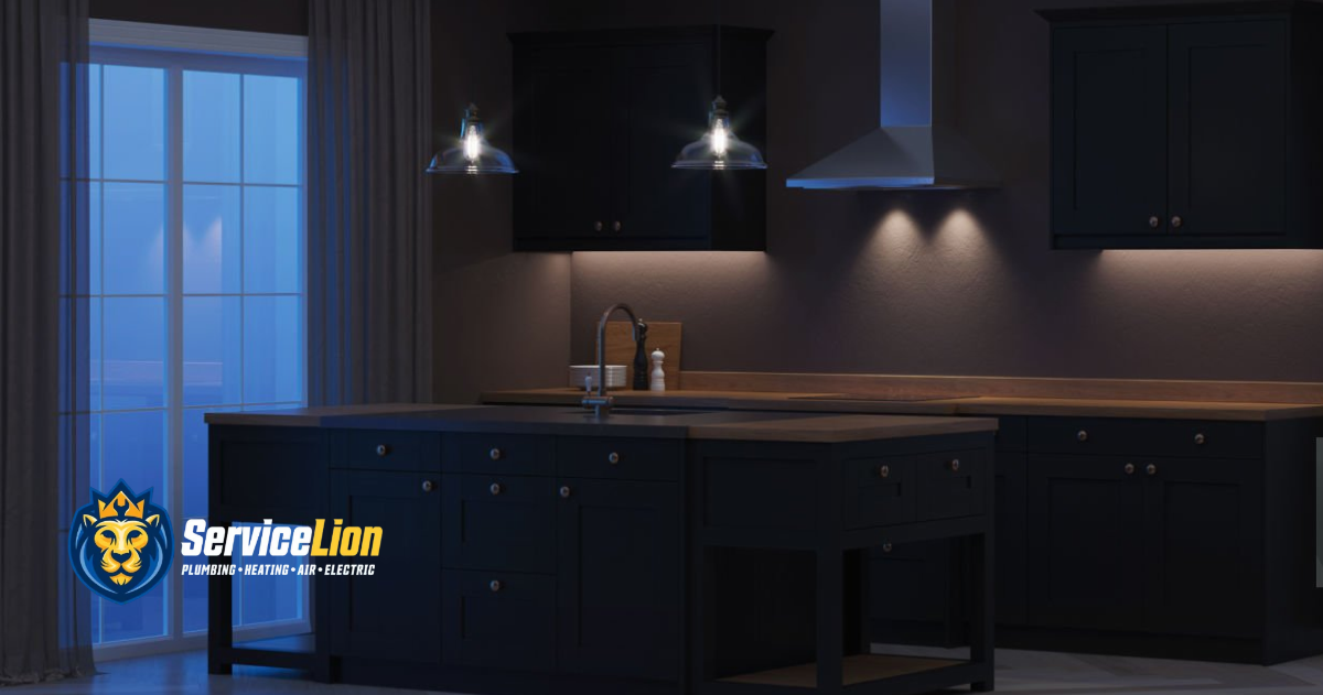 Dark modern kitchen with black cabinets, center island, and stainless steel fixtures; as a large appliance turns on, the pendant lights dim. Service Lion logo is in the lower left corner.