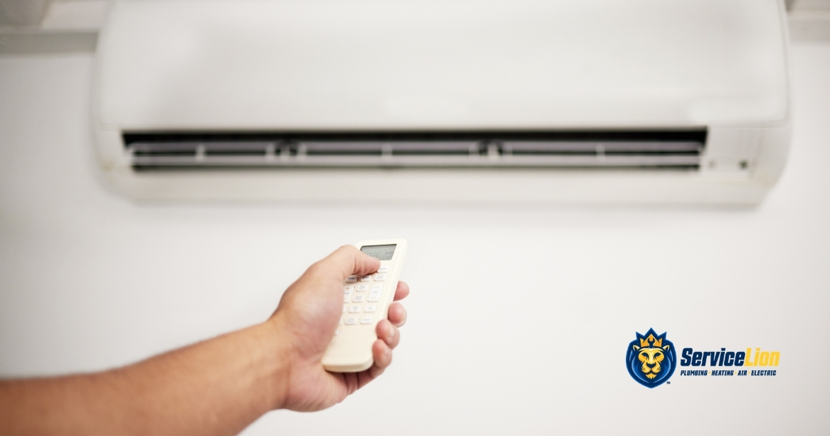 A person uses a remote control to operate a wall-mounted air conditioner, possibly addressing issues like AC short cycling or needing air conditioner troubleshooting. The Service Lion logo is visible in the bottom right corner.